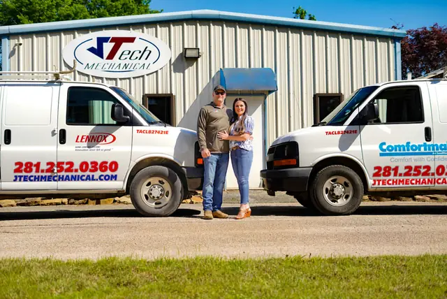 The owners of JTech Mechanical outside the shop between two service vans